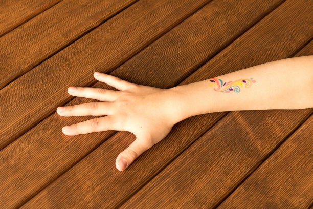木制背景上有婴儿纹身的小女孩的手掌图片下载