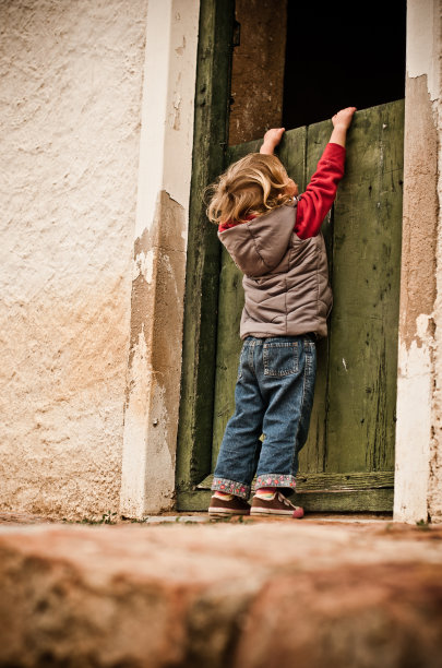 年轻的女孩在老房子的门口偷看图片下载