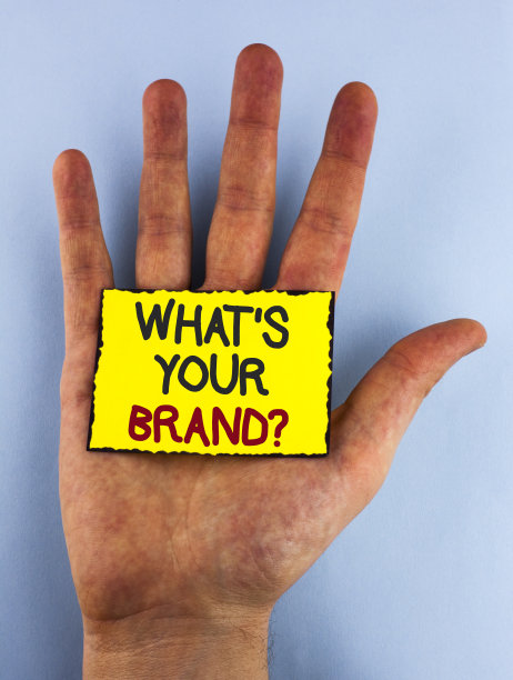 文字标志显示什么是你的品牌问题。概念照片定义个人商标识别公司写在黄色便利贴上放在手上在普通的背景。图片下载