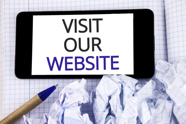 文字标志显示访问我们的网站。概念照片邀请观看网页链接到首页博客互联网写在手机上屏幕放在笔记本笔旁边。图片下载