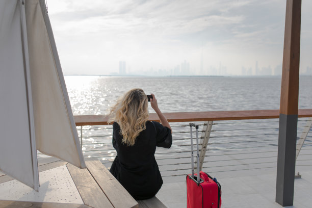 从海边拍摄城市照片的女子的背影图片下载