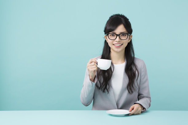 一个穿着西装拿着白色杯子的女人图片下载