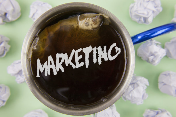 文字标志显示市场。概念照片广告从一家公司推销产品来推销写在茶杯里的揉皱的纸球上的东西，在朴素的绿色背景上。图片下载