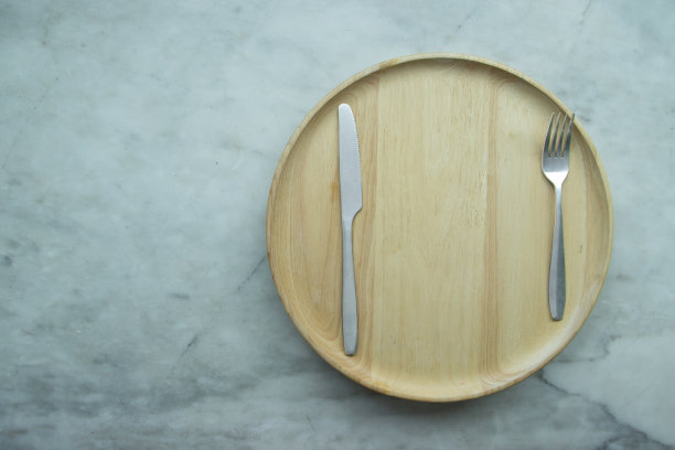 俯视图，将空盘子放在木制托盘上，放在灰色的花岗岩桌子上。图片下载