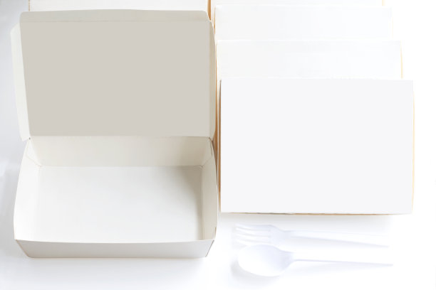 空白纸包白色盒子与塑料勺子和叉子在白色桌子的背景设计模拟快餐或产品和标志品牌。图片下载
