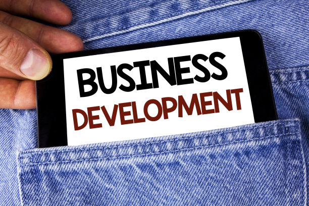 显示业务发展的概念性手写。商业图片文字开发和实施组织增长机会写在手机上，由男人在牛仔裤的背景。图片下载