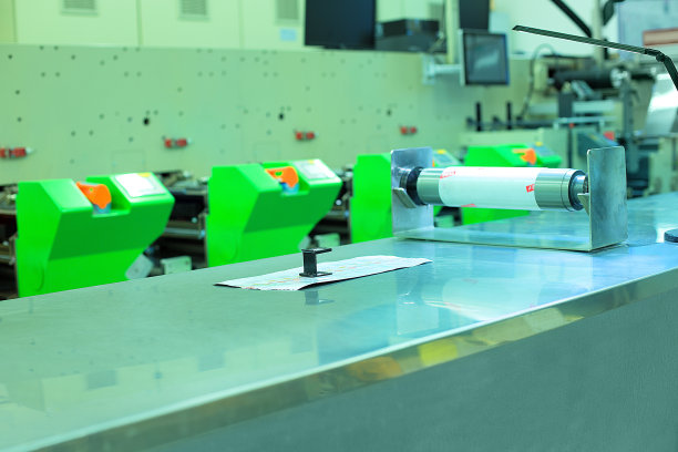 柔版印刷机背景图片，印刷样品，放大镜和印刷辊在工作台上。照片的轮转或柔印机。质量检查准备的概念。图片下载