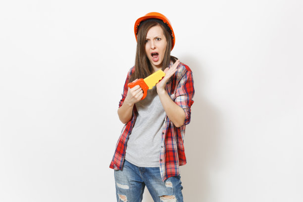 恼怒不满的女人在休闲衣服和保护橙色安全帽切割她的手与玩具锯孤立在白色背景。用于装修公寓房间的仪器。修理家里的概念。图片下载