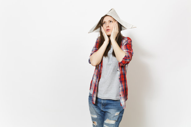 年轻关切的美丽女子在报纸帽子保持双手近脸孤立在白色的背景。公寓装修配件。修理家里的概念。广告版面复制。图片下载