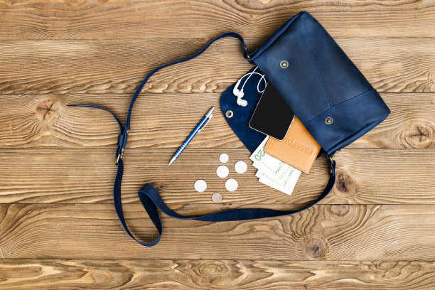 闭合的女人包打开与配件智能手机，护照，耳机，美元对木制俯视图，平躺图片下载