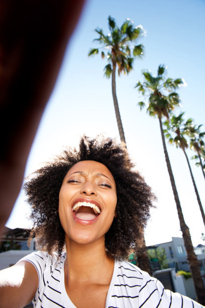 一幅年轻的非洲妇女的肖像，她在外面笑着，一头卷发图片下载