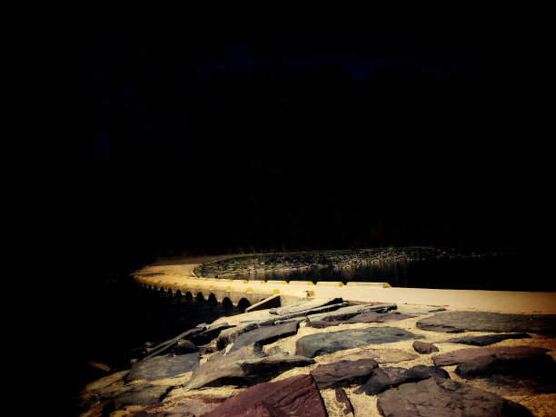 黄色的灯光在岩石和桥上闪烁，通向黑暗。图片下载