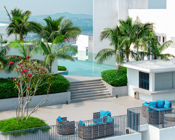 一个理想的异国情调的度假概念-顶视图美丽的屋顶，游泳池，休息区，绿树和棕榈树，山在地平线上。图片下载