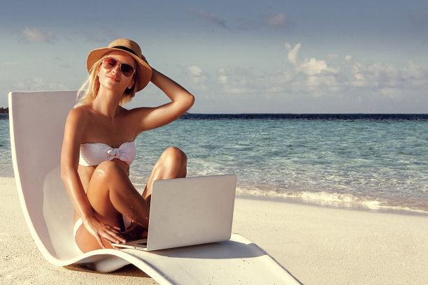 在沙滩上玩笔记本电脑的快乐女孩。图片下载