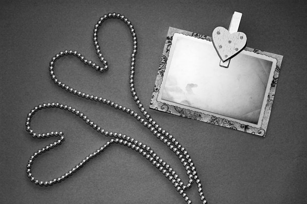 两颗心形珍珠项链和别针与旧相框在不同的颜色背景。图片下载