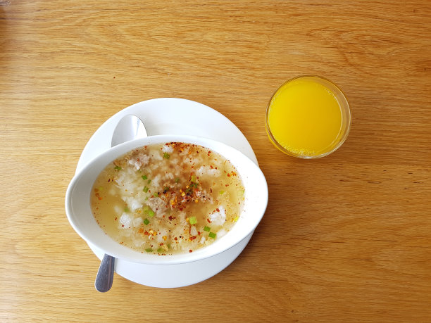 米饭猪肉煮早餐，橙汁和饮用水在木头桌子上。(亚洲传统食物)素材图片