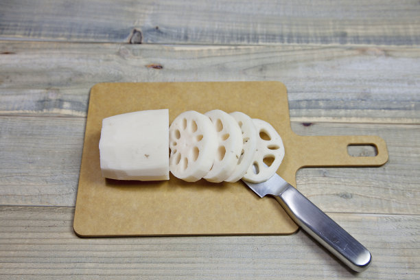 用菜刀将莲藕切在砧板上。在厨房准备食物图片下载