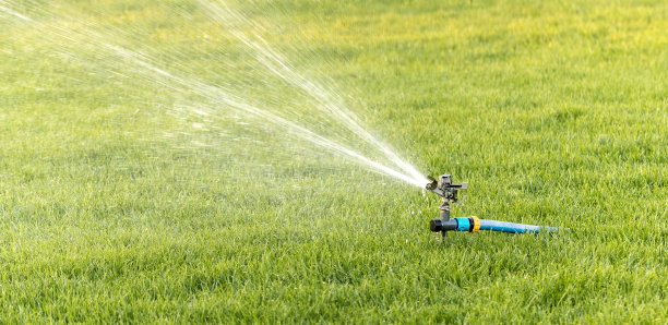 摆动灌溉洒水车的草坪在中午特写图片下载