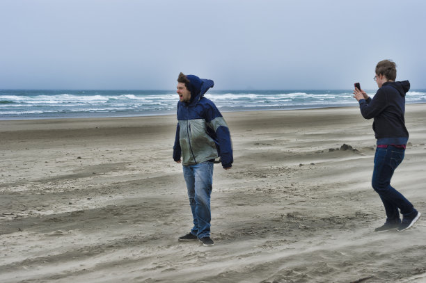 两个年轻人在多风的海滩上图片下载