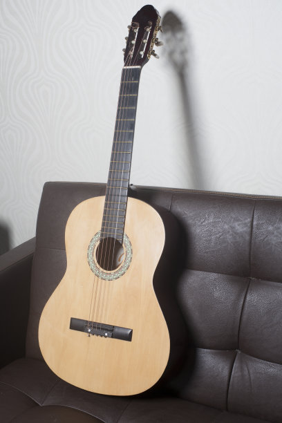 古典吉他倚在棕色皮沙发上图片下载