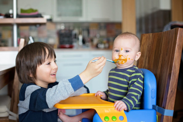 可爱的学前班男孩，给他的小弟弟喂蔬菜泥，宝宝吃土豆泥图片下载