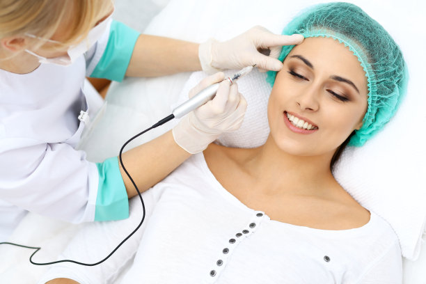 专业美容师在女人脸上纹眉。美容院永久眉妆，特写。美容应用素材图片