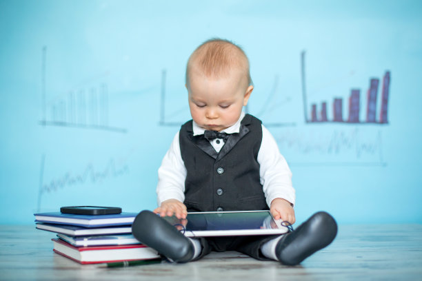 可爱的蹒跚学步的小男孩，穿着西装和鞠躬，打电话和玩平板电脑图片下载