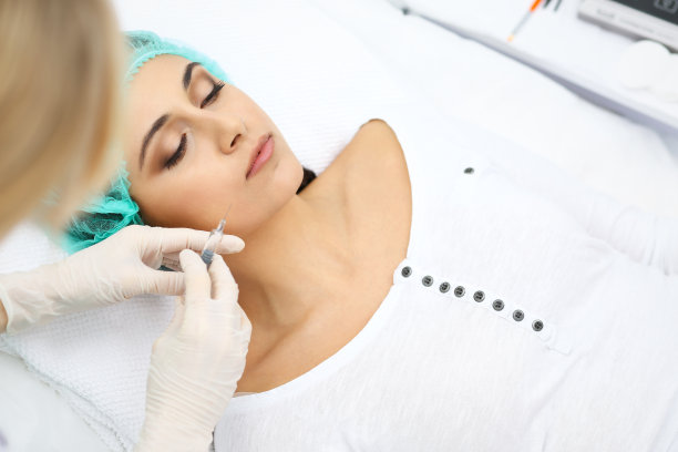 专业美容师在脸部、嘴唇进行注射。年轻女子得到注射器填充面部轮廓或扩大。脸部老化、年轻化和补水程序素材图片