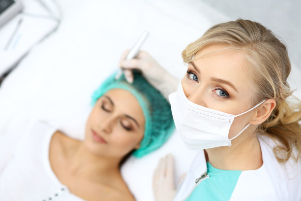 专业美容师在女人脸上纹眉。美容院永久眉妆，特写。美容应用素材图片