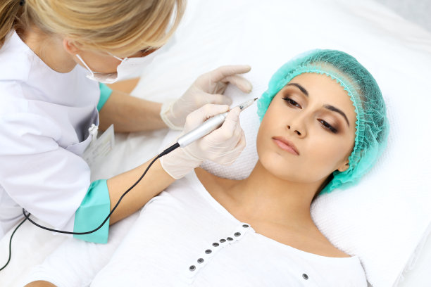 专业美容师在女人脸上纹眉。美容院永久眉妆，特写。美容应用素材图片