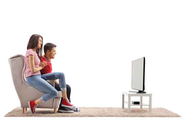 一对年轻夫妇坐在扶手椅上看电视图片下载