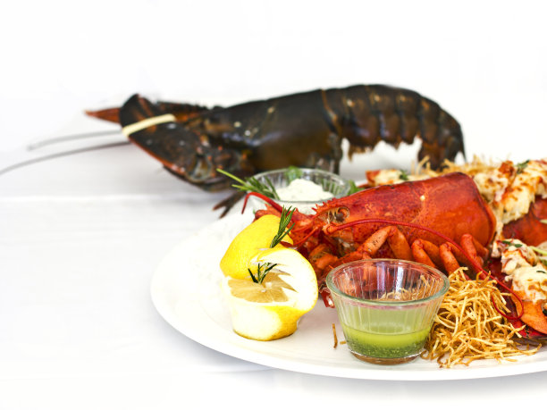 活龙虾和熟龙虾与蔬菜一起放在一个白色的盘子里。孤立的图片下载