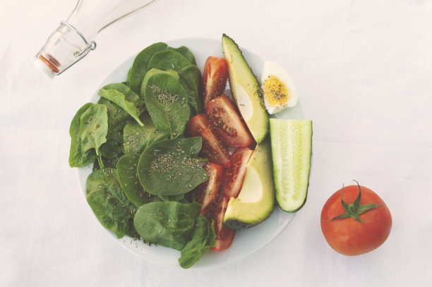 平铺着一碗沙拉，白桌布上放着香料和油。健康的素食图片下载