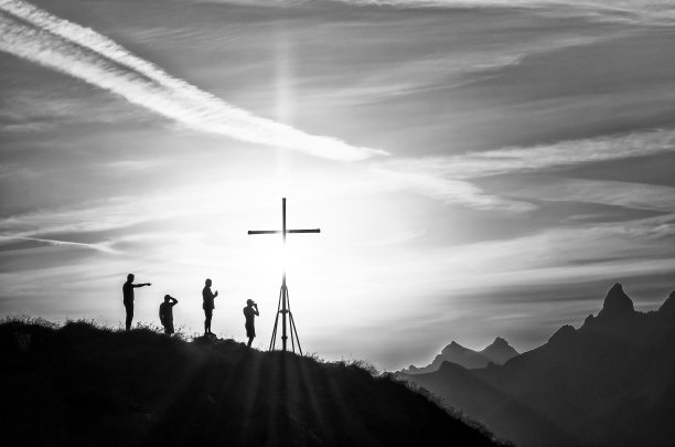 四个徒步旅行者在日出时在欧洲阿尔卑斯山的顶峰交叉图片下载