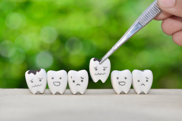 牙科医生用镊子套出蛀牙模型，以达到牙科保健的理念图片下载