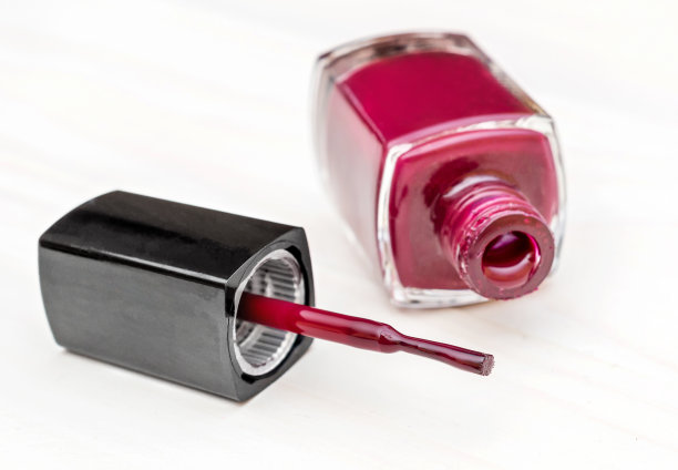 白色木桌上，用刷子打开一瓶指甲油。关闭了。图片下载