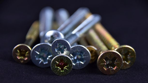 黑色背景上的凹头螺钉由黄铜、铜和不锈钢制成图片下载