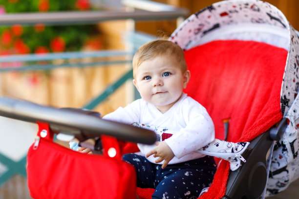 可爱的小女孩坐在婴儿车里等妈妈。蓝眼睛的快乐微笑的孩子。图片下载