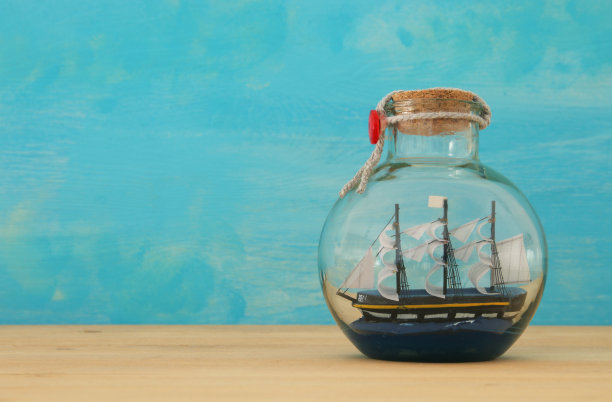 航海概念形象与帆船在木桌上的瓶子。有选择性的重点。图片下载