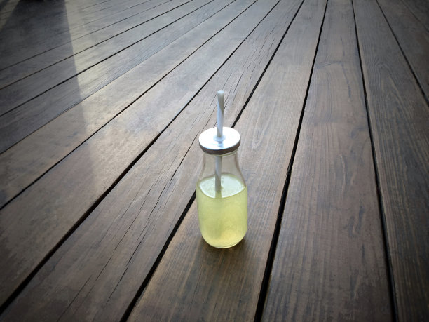 在晚霞的木头背景下，柠檬水瓶子。图片下载