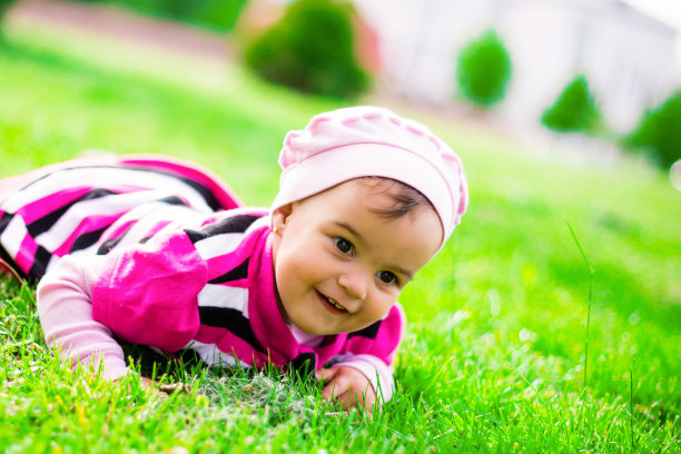 穿粉红色衣服的小女孩在草地上笑图片下载