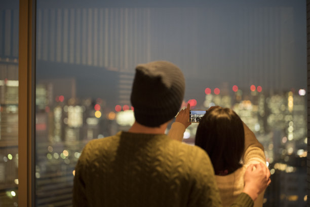 一对夫妇在一个有夜景的休息室里拍照图片下载