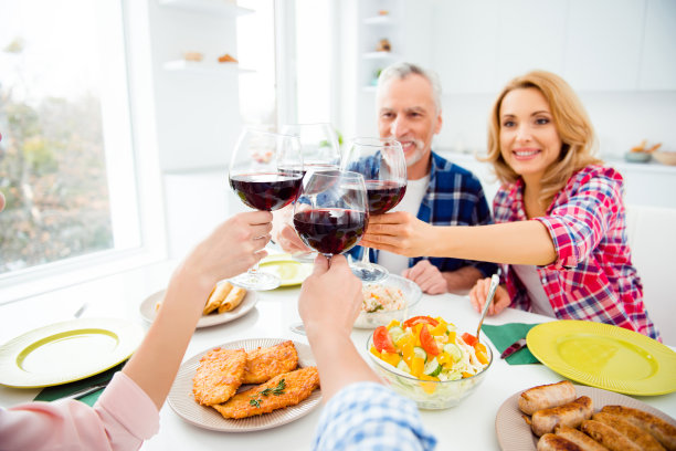 这是一对时尚、迷人、欢快的老年夫妇在家里和孩子们一起用餐的照片，公寓里的酒杯与红酒、酒精、开胃菜摆在桌上图片下载