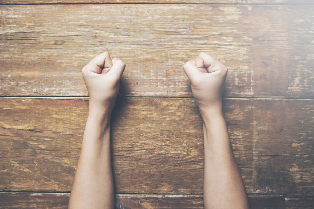 女人握紧拳头放在一张木桌上图片下载