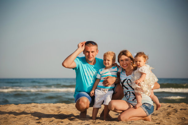 年轻幸福的家庭和小孩子一起在海边玩，快乐的生活方式家庭概念图片下载