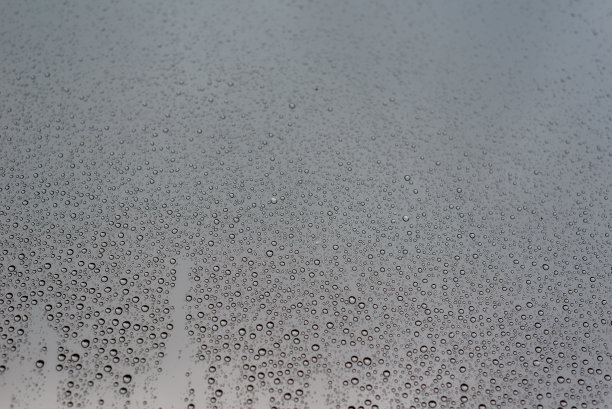 雨点落在窗玻璃上，以多云的天空为背景图片下载