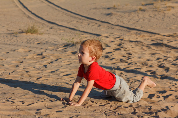 日落时分，黄沙上的小男孩图片下载