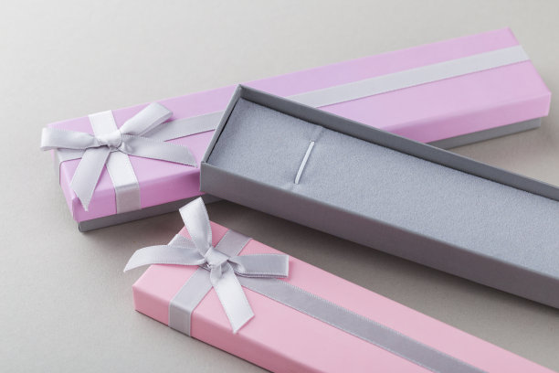 打开灰色背景上带丝带蝴蝶结的粉色礼盒图片下载