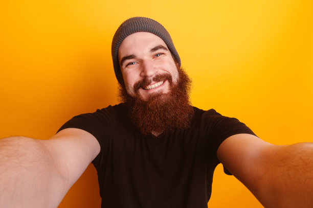 满脸胡须的男子在橙色背景下自拍图片下载