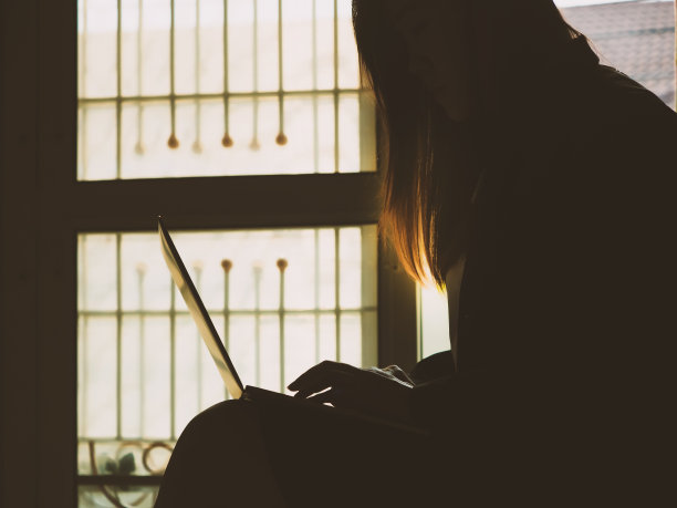 商业和女性权力的概念从剪影的黑色套装妇女工作和使用笔记本电脑和移动电话在她的家庭办公室在窗边图片下载